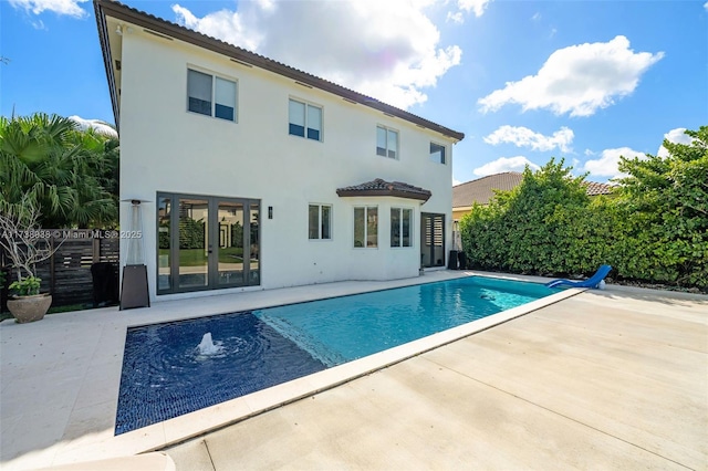 rear view of house featuring a fenced in pool, french doors, stucco siding, a patio area, and fence