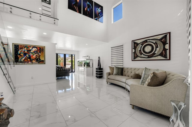 living area with marble finish floor, recessed lighting, a towering ceiling, and baseboards