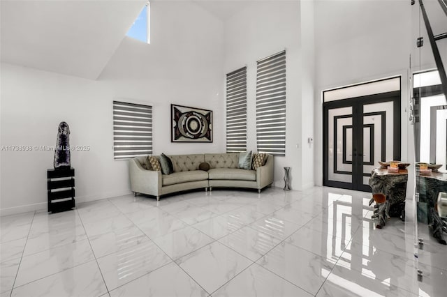 unfurnished living room with marble finish floor, a high ceiling, and baseboards