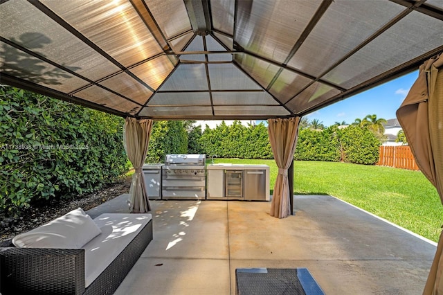 view of patio with a fenced backyard, a grill, an outdoor kitchen, and a gazebo