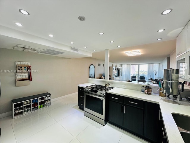 kitchen with visible vents, gas range, dark cabinets, light countertops, and recessed lighting