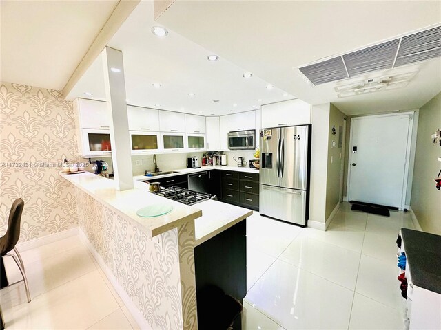 kitchen featuring white cabinetry, light tile patterned floors, stainless steel appliances, and kitchen peninsula