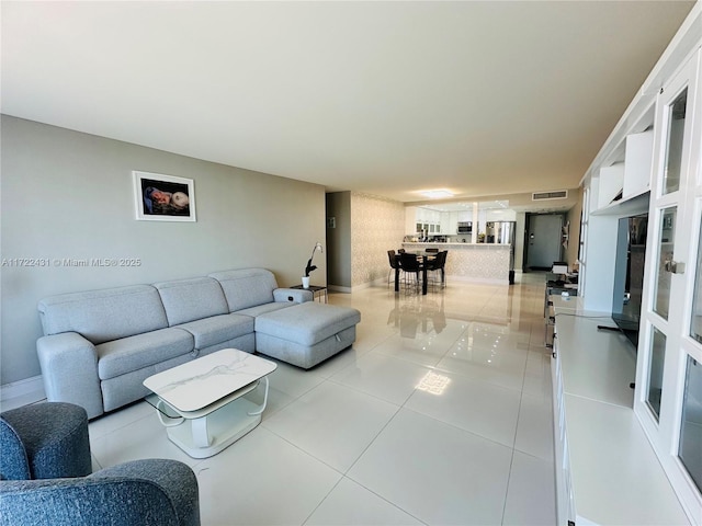 living area with light tile patterned flooring, visible vents, and baseboards