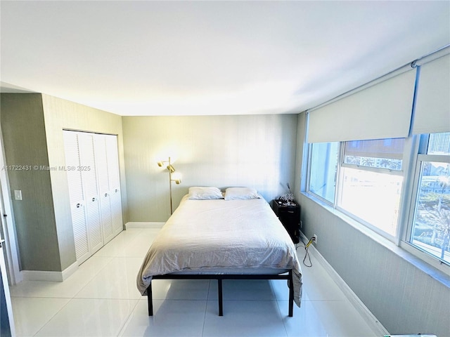 bedroom with baseboards, a closet, and light tile patterned flooring