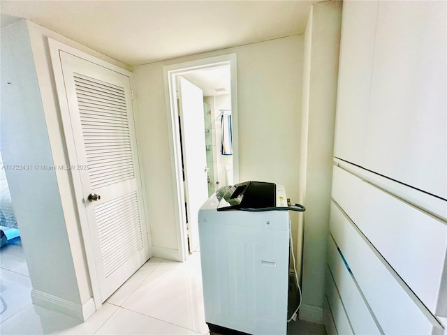 interior space featuring baseboards, washer / clothes dryer, and light tile patterned flooring