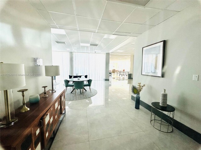 hall with light tile patterned floors and a drop ceiling