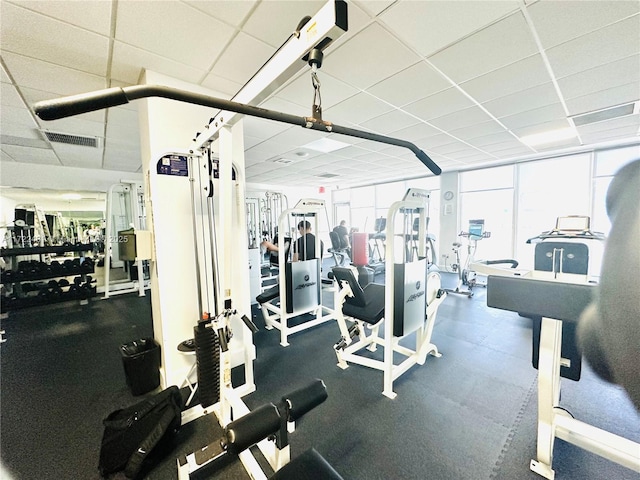 gym with expansive windows, visible vents, and a drop ceiling