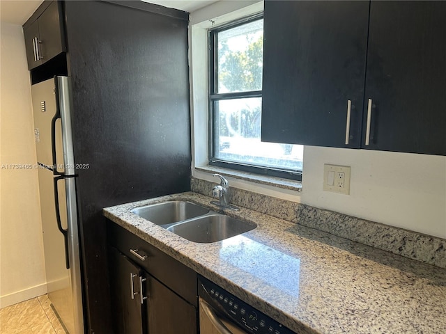 kitchen featuring light tile patterned floors, dishwasher, light stone counters, freestanding refrigerator, and a sink