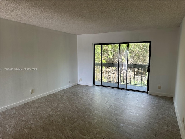 empty room with a textured ceiling and baseboards