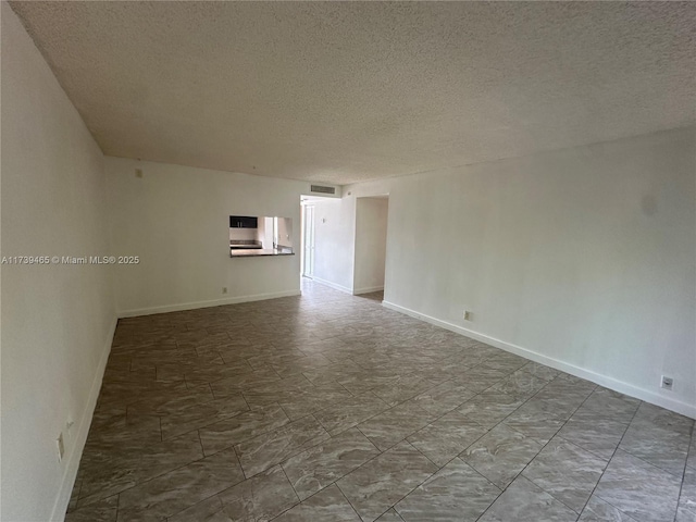 unfurnished room featuring baseboards, visible vents, and a textured ceiling