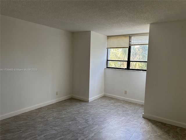 empty room featuring a textured ceiling and baseboards