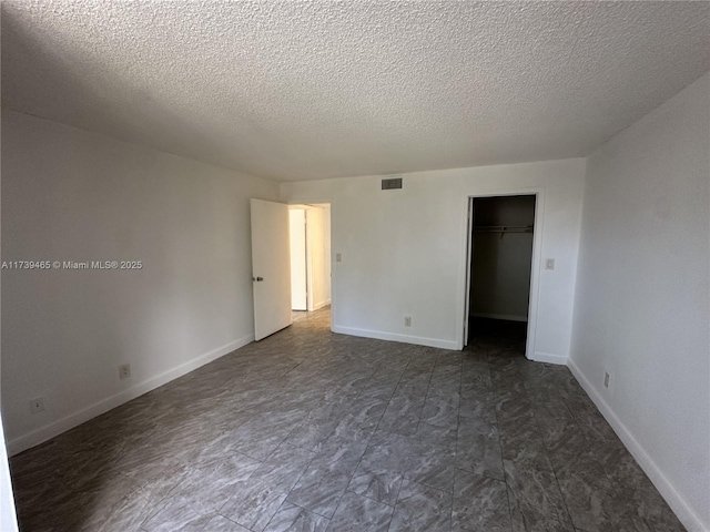 unfurnished bedroom with a walk in closet, visible vents, and baseboards