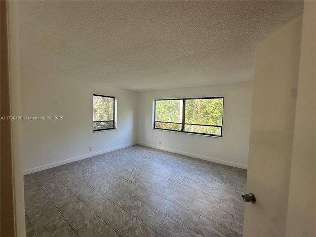 empty room featuring a textured ceiling and baseboards