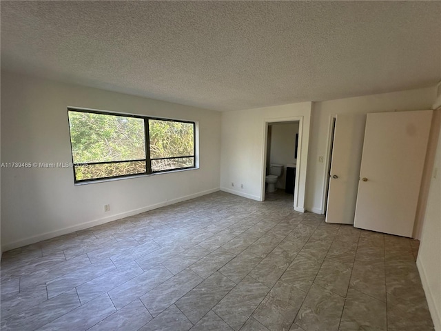 unfurnished bedroom with baseboards, a textured ceiling, and ensuite bathroom