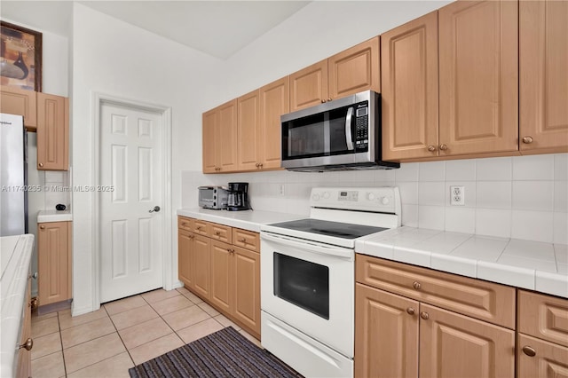 kitchen with backsplash, light tile patterned floors, tile countertops, and stainless steel appliances