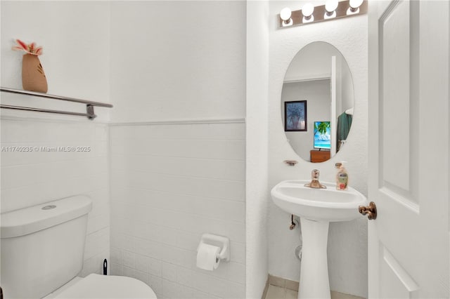 bathroom with tile walls and toilet