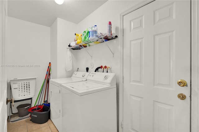 clothes washing area featuring light tile patterned floors, independent washer and dryer, and a textured ceiling