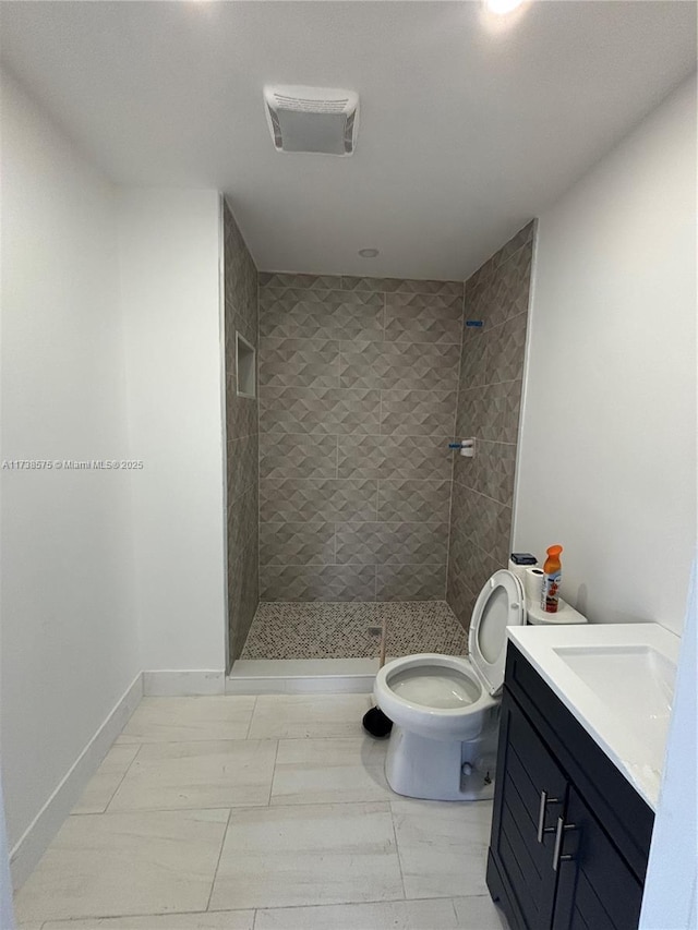 bathroom with vanity, toilet, and a tile shower