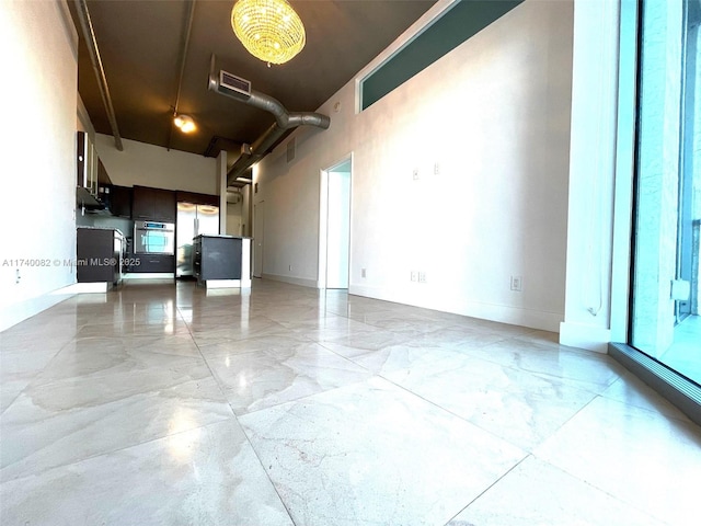 interior space featuring a towering ceiling, marble finish floor, and baseboards