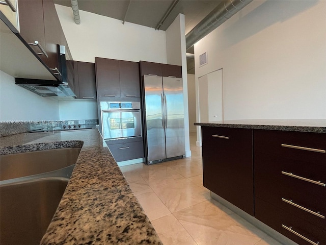 kitchen featuring visible vents, modern cabinets, dark stone countertops, a high ceiling, and stainless steel appliances