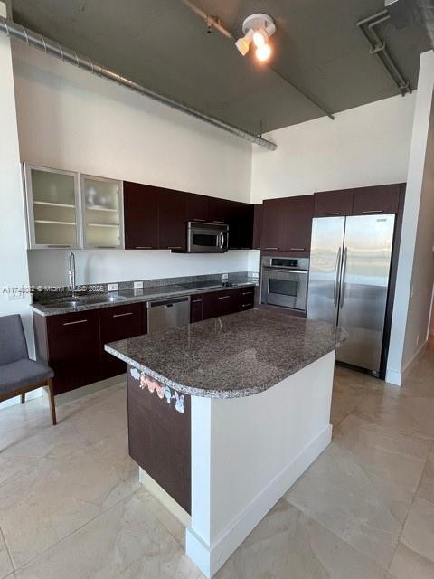 kitchen featuring sink, dark brown cabinets, a high ceiling, and appliances with stainless steel finishes