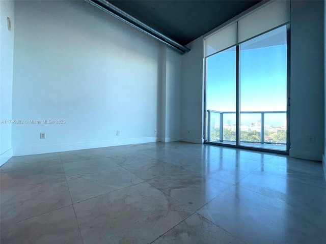 empty room featuring floor to ceiling windows and baseboards