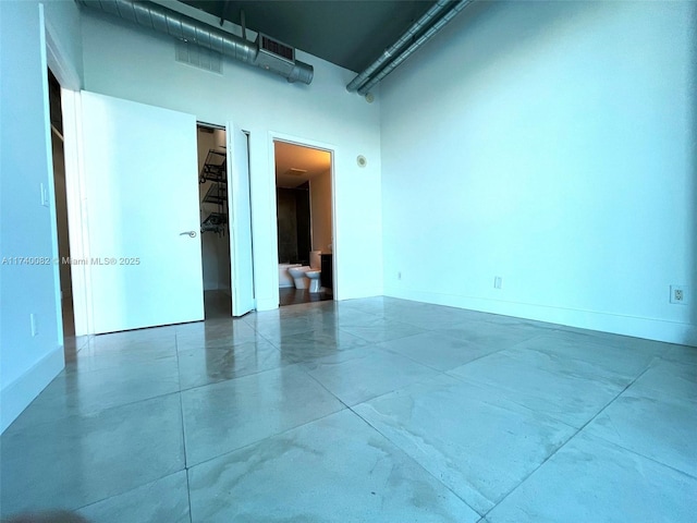 unfurnished room with baseboards, a high ceiling, and visible vents