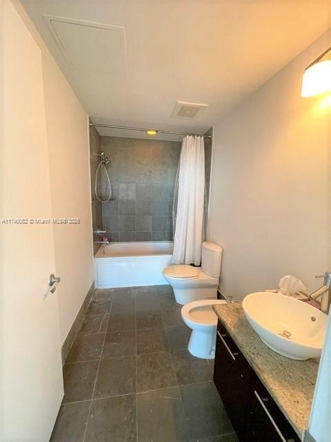 full bathroom featuring toilet, a bidet, vanity, shower / bathtub combination with curtain, and tile patterned flooring