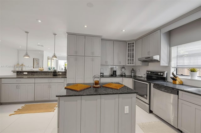 kitchen with sink, appliances with stainless steel finishes, pendant lighting, a kitchen island with sink, and decorative backsplash