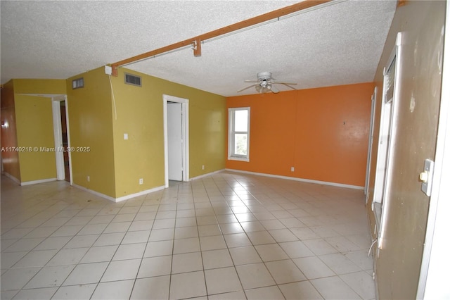 empty room with ceiling fan, a textured ceiling, and light tile patterned floors