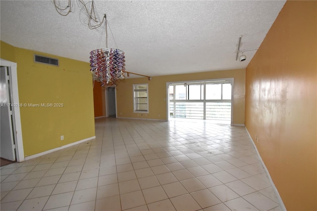 spare room with light tile patterned flooring, track lighting, and a textured ceiling