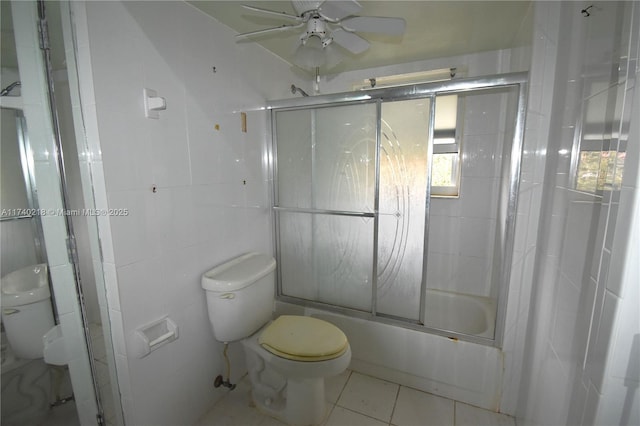 bathroom featuring toilet, tile walls, ceiling fan, tile patterned flooring, and enclosed tub / shower combo