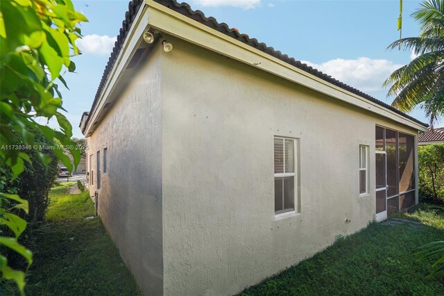 view of home's exterior with a sunroom and a lawn