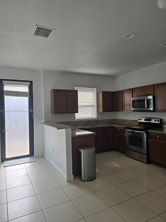 kitchen featuring light tile patterned flooring, appliances with stainless steel finishes, and kitchen peninsula