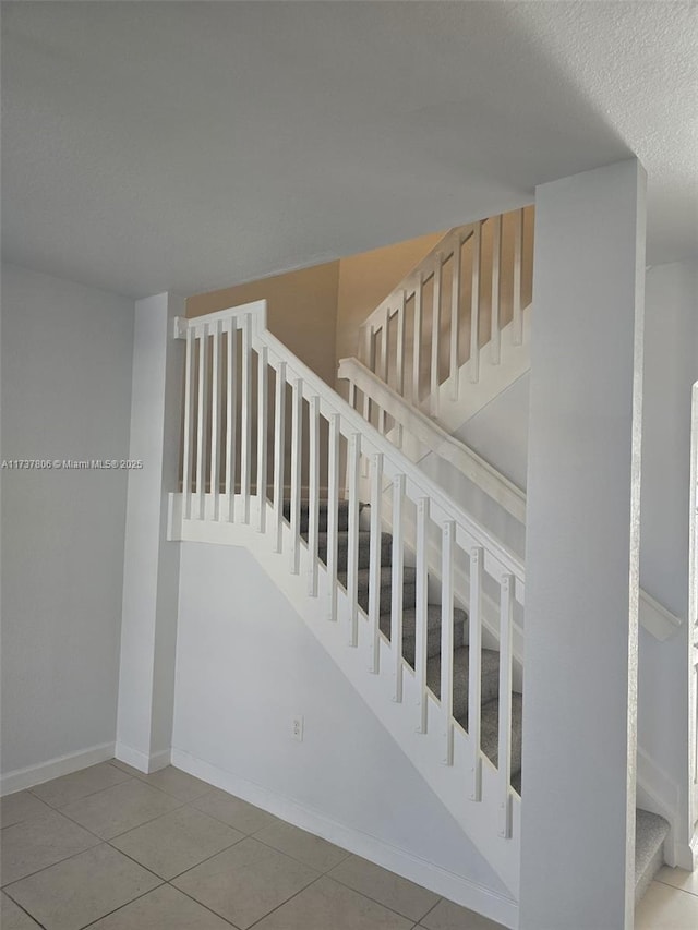 stairway with tile patterned flooring and a textured ceiling