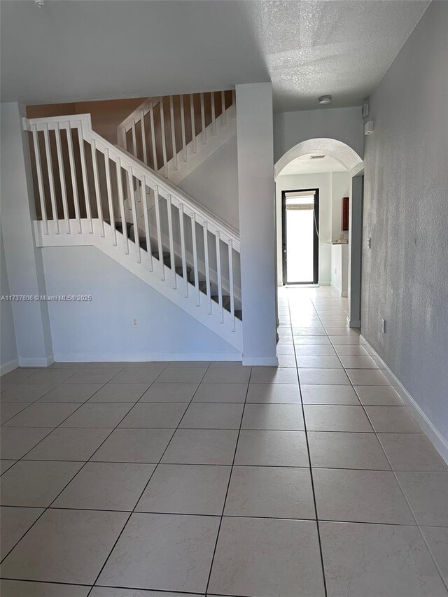 corridor with tile patterned floors and a textured ceiling