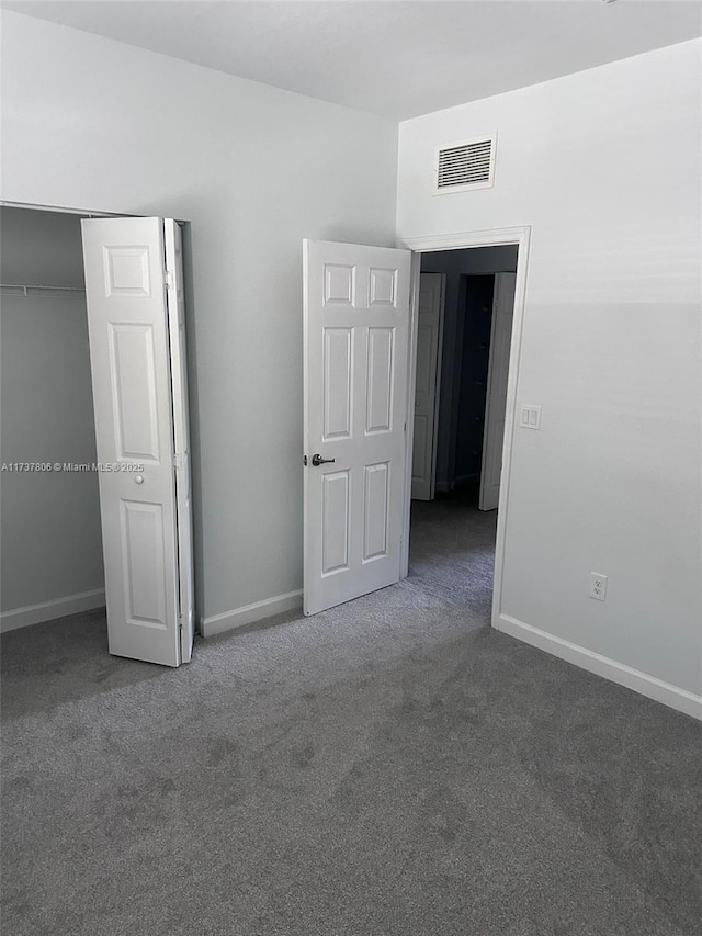 unfurnished bedroom with dark carpet and a closet