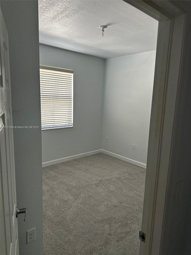 carpeted empty room featuring a textured ceiling