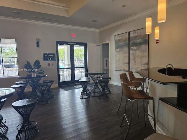 dining area with ornamental molding, dark wood-type flooring, a wealth of natural light, and french doors