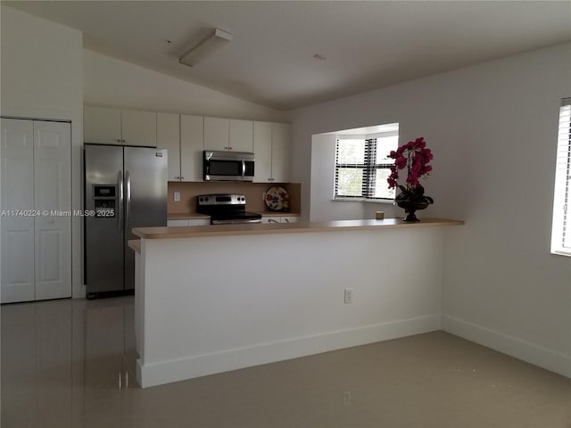 kitchen featuring vaulted ceiling, appliances with stainless steel finishes, white cabinets, and kitchen peninsula