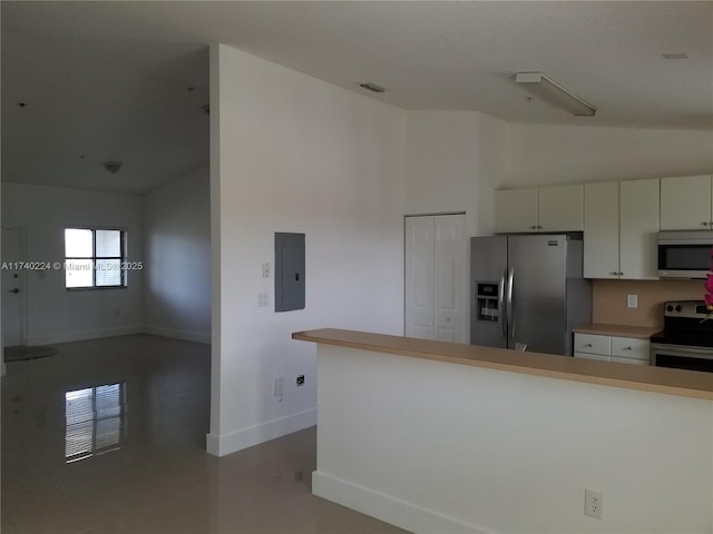 kitchen featuring white cabinets, lofted ceiling, appliances with stainless steel finishes, and electric panel