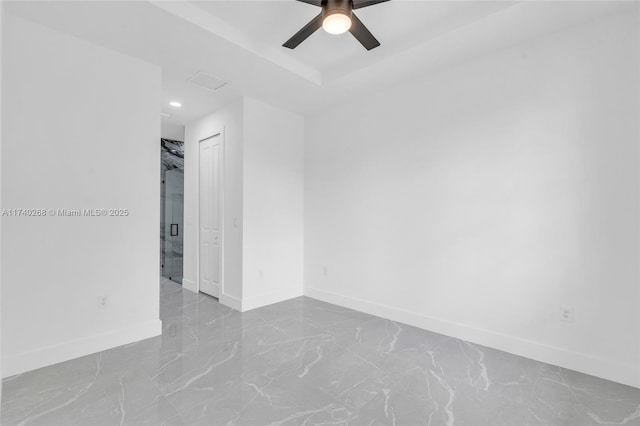 spare room with a tray ceiling and ceiling fan