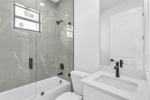 full bathroom featuring toilet, vanity, and shower / bath combination with glass door