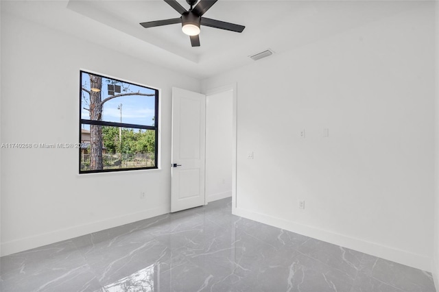 unfurnished room featuring ceiling fan and a tray ceiling