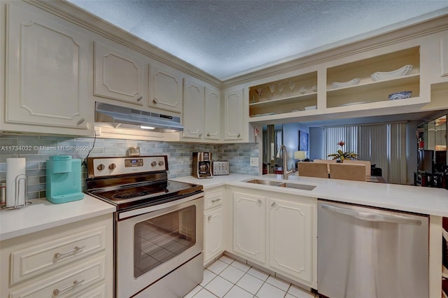 kitchen with sink, decorative backsplash, light tile patterned floors, stainless steel appliances, and a textured ceiling