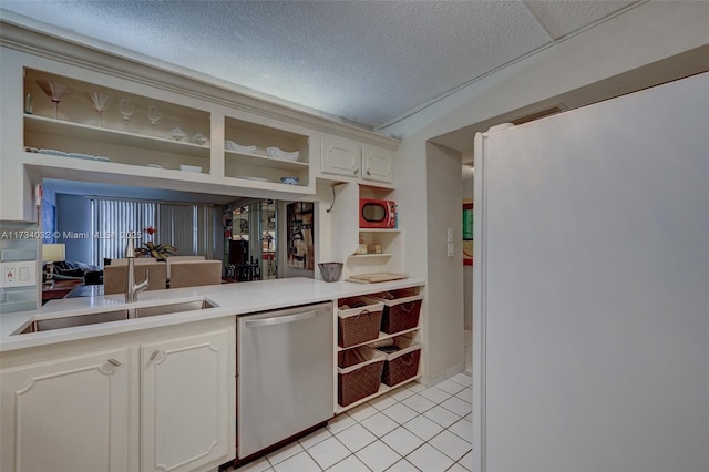 kitchen featuring sink, light tile patterned floors, dishwasher, white refrigerator, and a textured ceiling