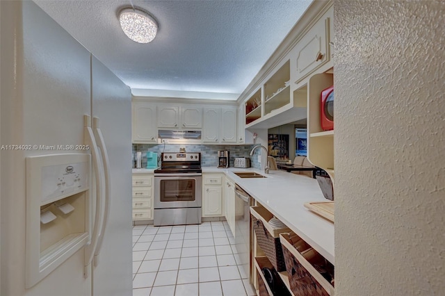 kitchen with sink, backsplash, light tile patterned floors, stainless steel appliances, and a textured ceiling