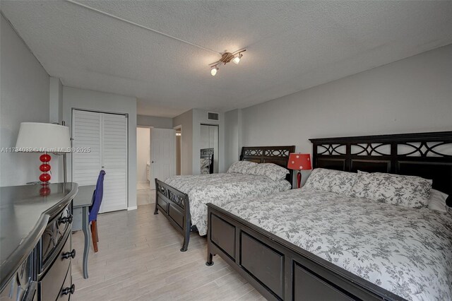 bedroom featuring a textured ceiling and light hardwood / wood-style flooring