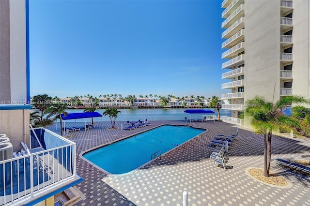 view of pool featuring a water view and a patio