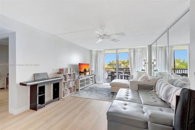 living room featuring floor to ceiling windows, a ceiling fan, a textured ceiling, wood finished floors, and baseboards